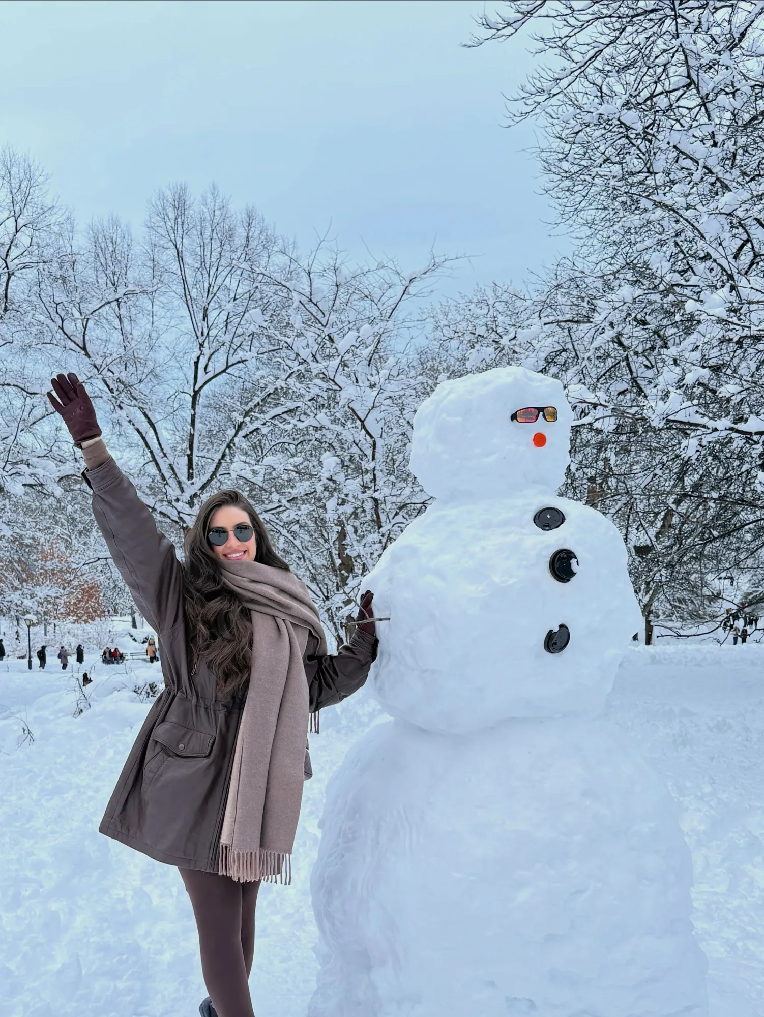 Mulher ao lado de boneco de neve em paisagem branca